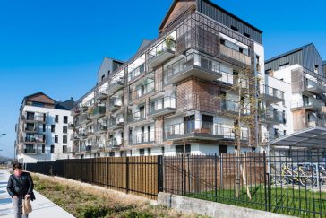 Logements aux abords d'une rue piétonne, de l'écoquartier de Montévrain. Un passant se balade sur le sentier