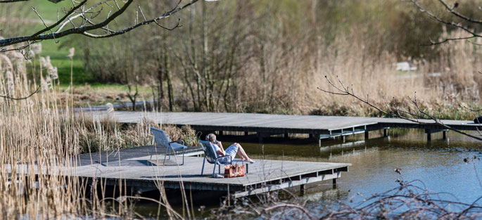 Crédit : ©Epamarne / Paysagiste : J. Osty / Photo : Antoine Meyssonnier Un riverain se repose sur un transat sur l'une des rives de l'étang des grives, du parc du Génitoy, situé dans le centre ville de Bussy Saint-Georges
