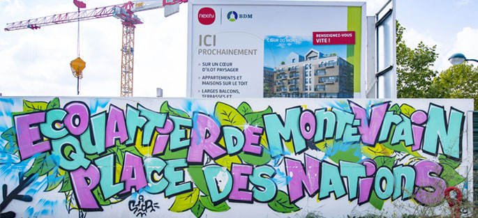Fresque de lettrage sur une palissade de chantier du programme de logements coeur du Montévrain. On peut y lire "Écoquartier de Montévrain - Place des Nations"
