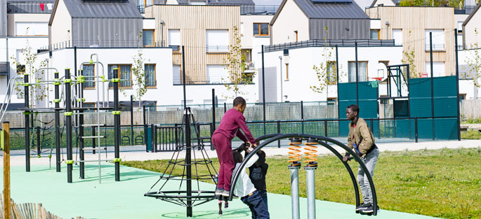 Des enfants se balancent sur une balançoire de l'aire de jeux aux abords de quelques logements du lotissement Métaflore, dans l'écoquartier de Montévrain