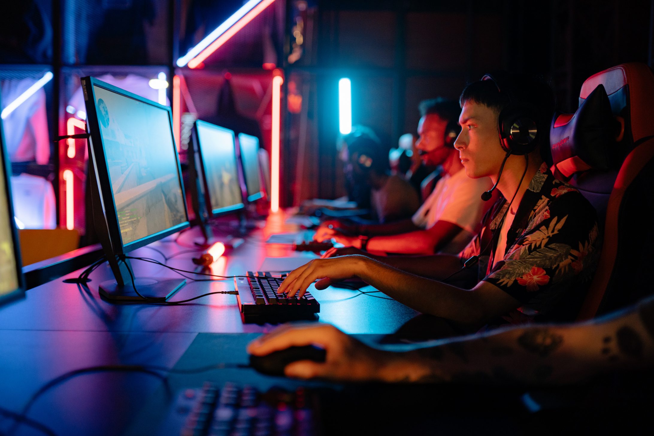 Des hommes dotés de casques audio, jouant au jeu vidéo sur un ordinateur fixe